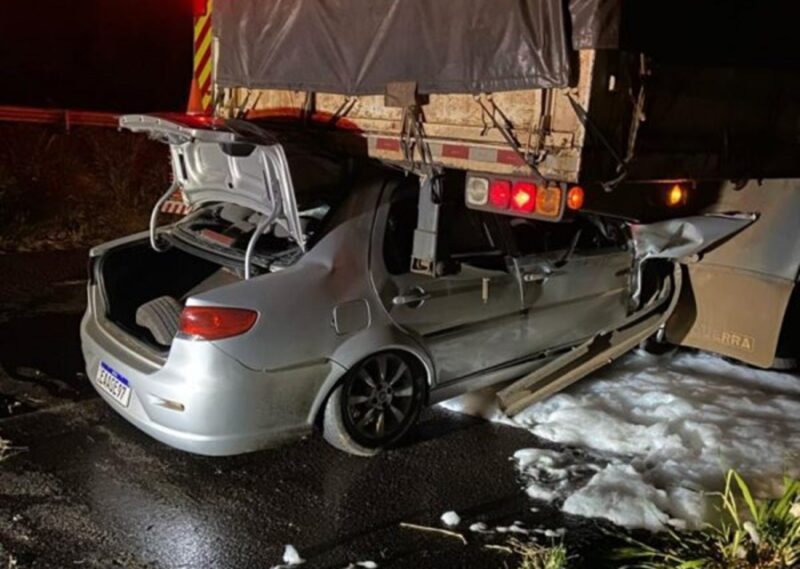 BR 376 – Siena vai parar embaixo de caminhão e motorista tem lesões gravíssimas